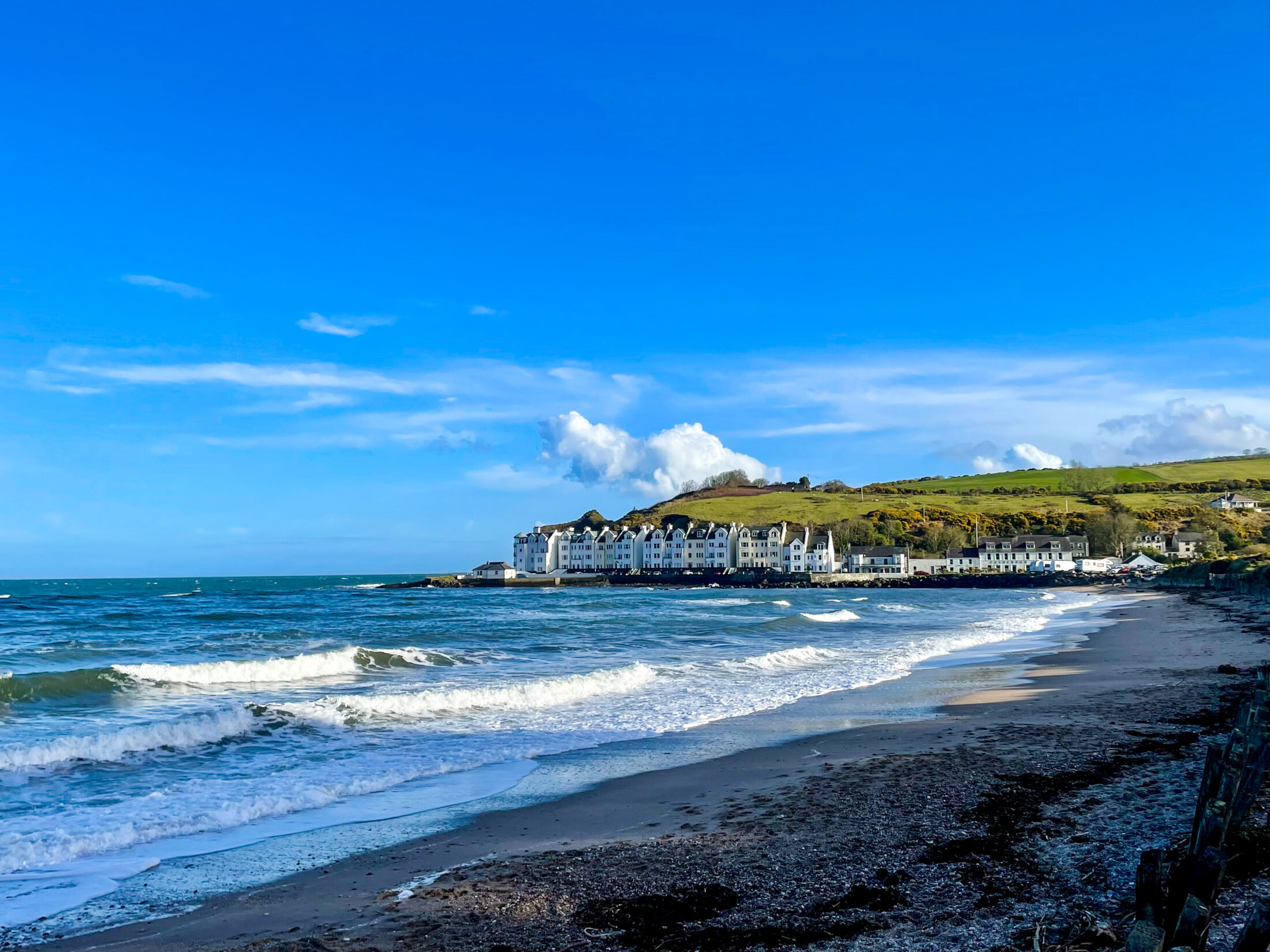 Nordirland Roadtrip Sehenswürdigkeiten: Strandabschnitt mit Brandung und Klippen entlang der Causeway Coastal Route
